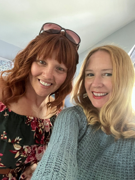 two individuals taking a selfie in front of a window